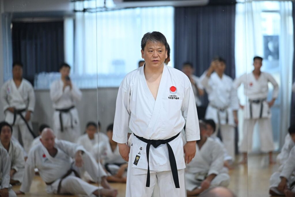 Taniyama Shihan standing in front of seated participants